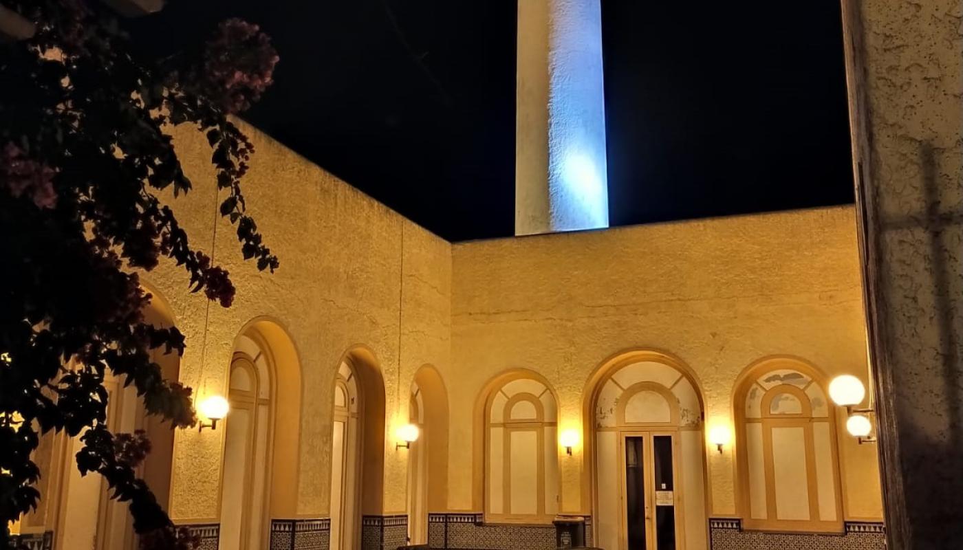 Foto nocturna del patio del edificio del Museo donde se ve el piso en forma de damero, una fuente central y en el fondo las salas del museo y la torre