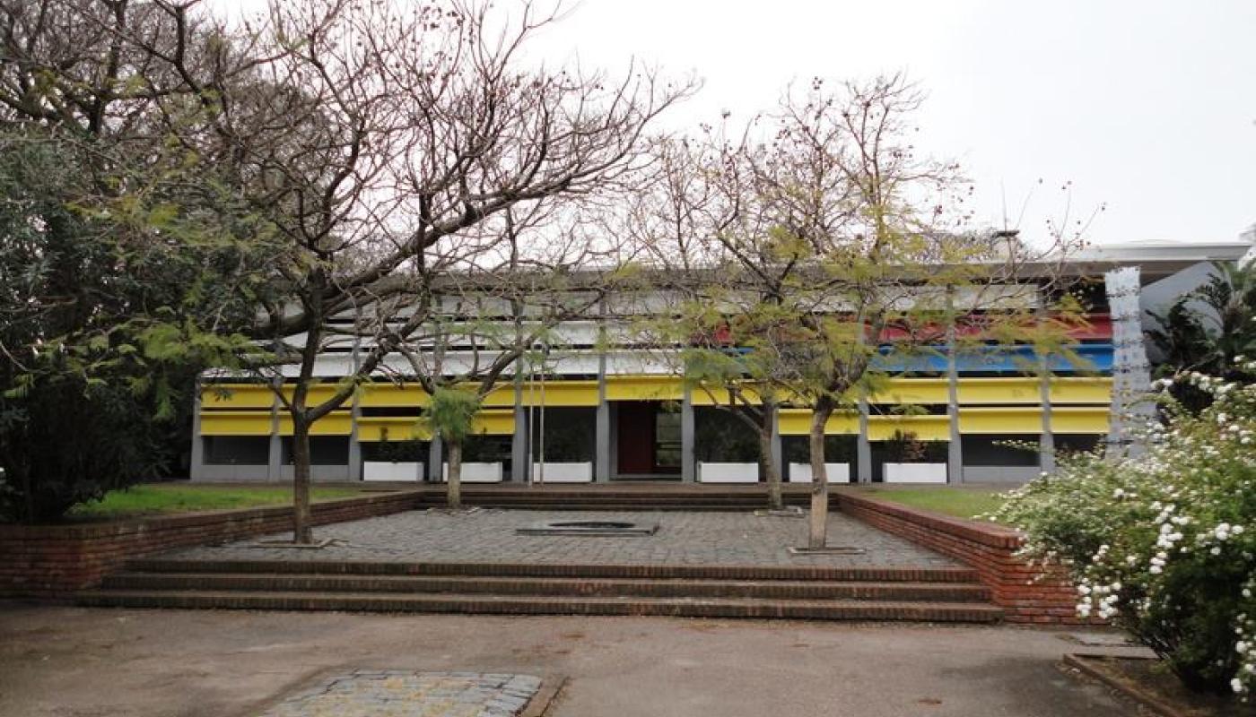 Foto exterior invernal del Museo. Fachada moderna en colores varios. Patio amplio con escalinatas. 