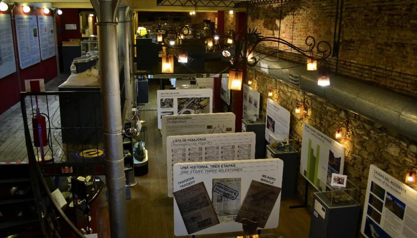 La foto refleja la sala principal del museo, su iluminación a través de focos así como paneles ilustrativos con imagenes y texto de la tragedía de los Andes