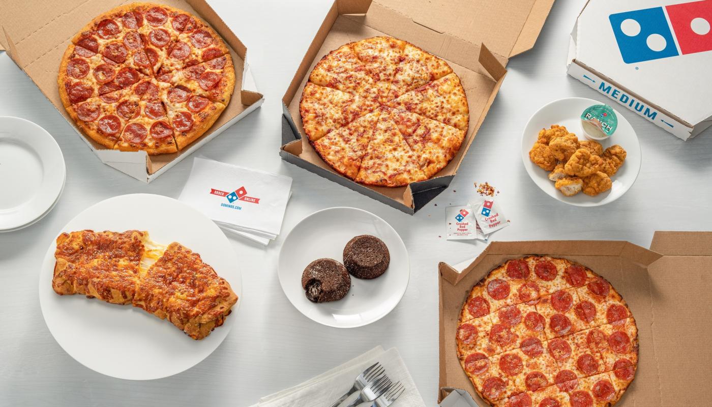 diferentes productos que Domino's :pizza pepperoni, stromboli, pizza muzzarella, nuggets y volcan de chocolate todo sobre una mesa presentado
