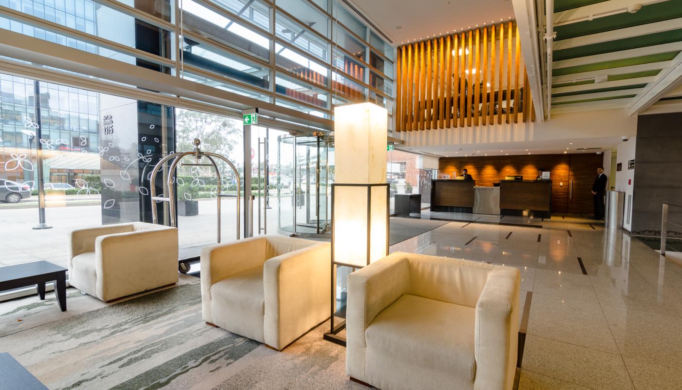 Lobby del hotel con la recepción al fondo y living en el centro con pared vidriada al exterior