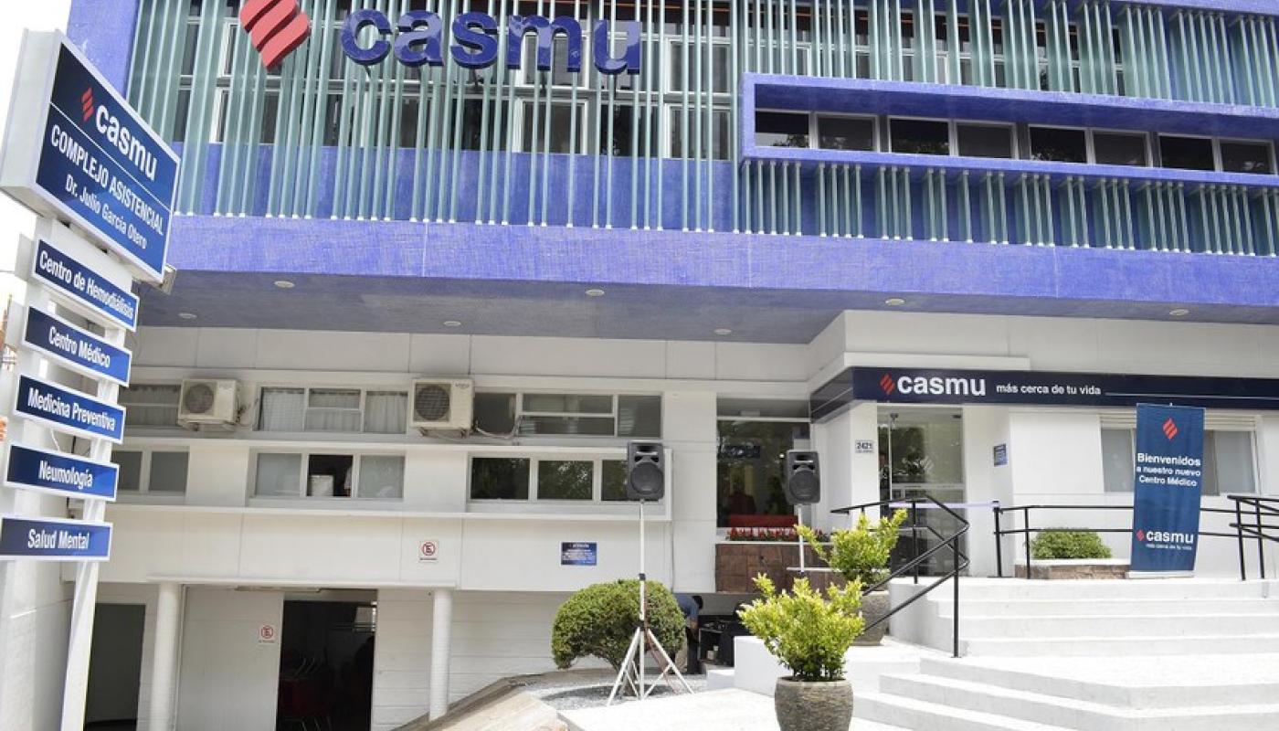 Edificio moderno con escalina principal blanca y rampa accesible. Frente blanco y azul como los colores de la empresa. Logo en diferentes partes de la fachada. 
