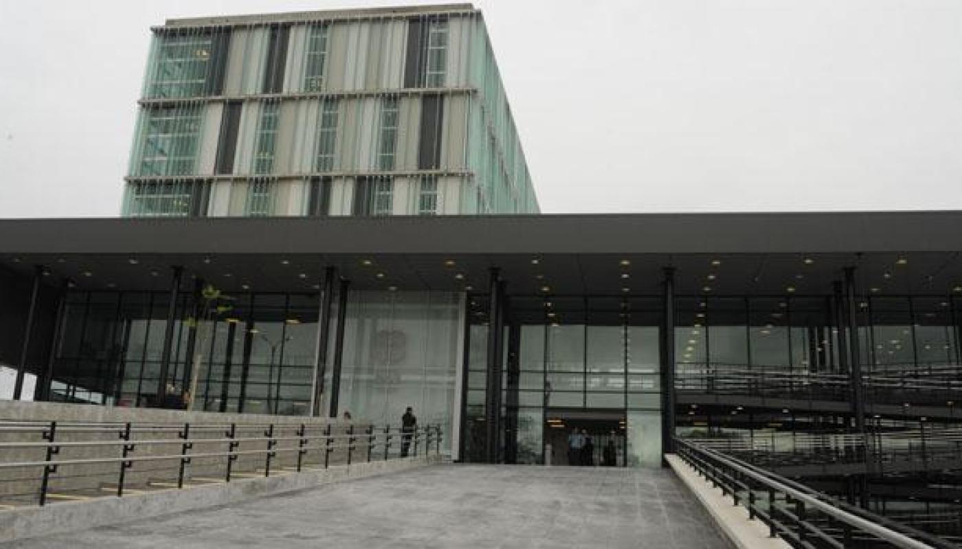 Ingreso mediante rampa de material. Edificio moderno todo vidriado con varios pisos. Formas cuadradas y rectangulares del edificio.
