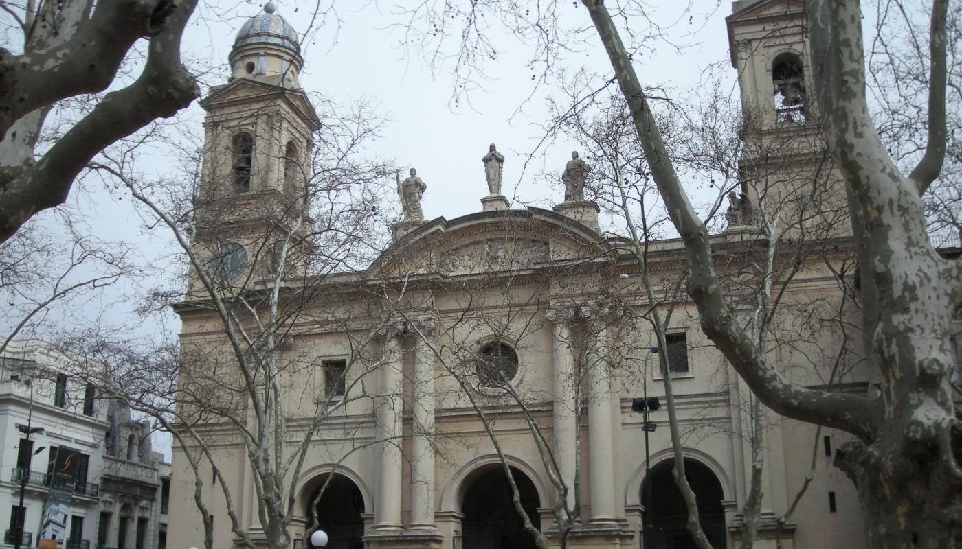 Fachada de la Iglesia Matriz. Al centro un gran portal, con dos columnas a cada lado y un vitral redondo encima. Arriba, en el techo, hay tres estatuas.
