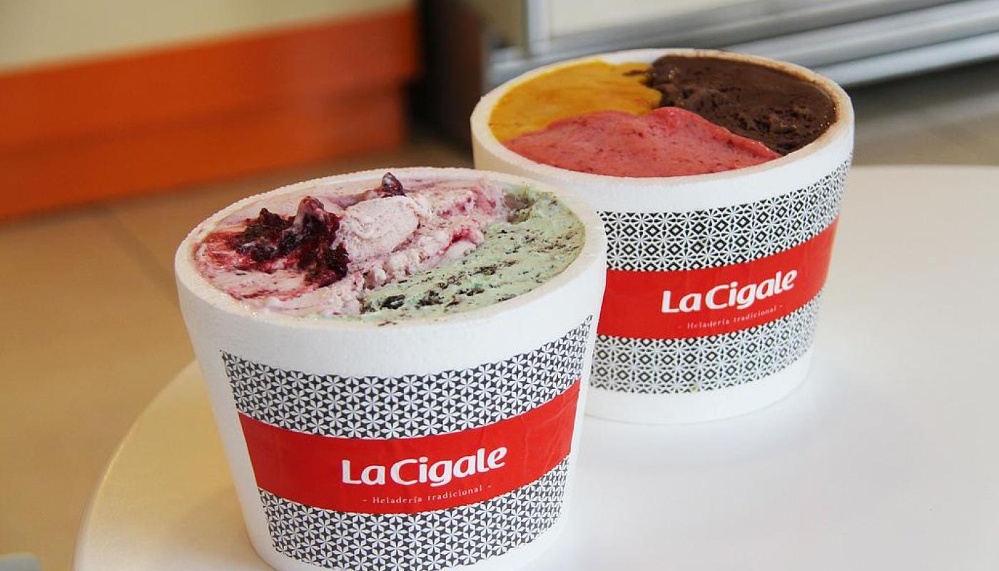 dos vasitos de helados con el logo de la empresa con gustos de helados distintos muy coloridos sobre una mesa