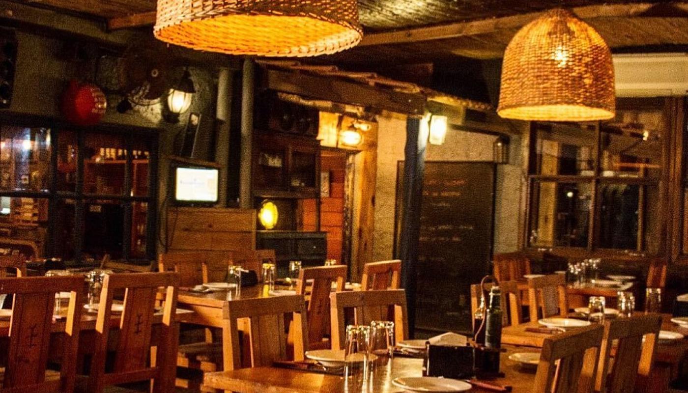 Foto del salón principal decorado con madera y lamparas de mimbre así como artículos de pesca dándole un toque rústico