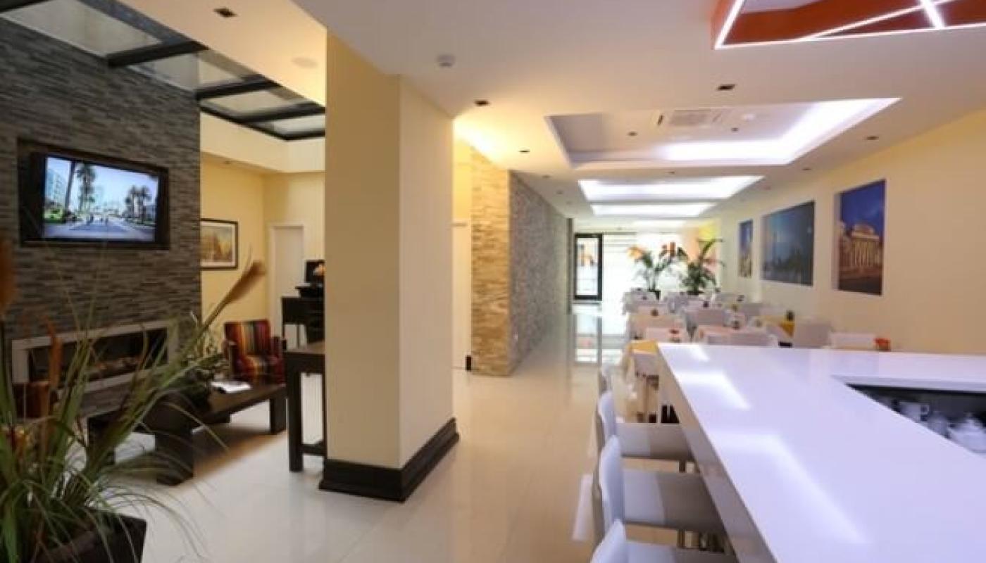 Interior del hotel. Hay algunas mesas con sillas y una barra con bancos altos.
