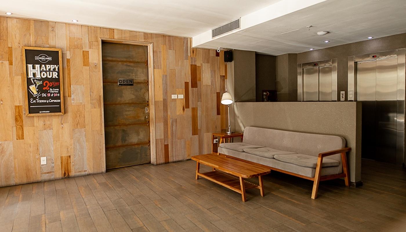 Parte del lobby del hotel. Hay un sofá de tres cuerpos y una mesa ratona de madera.