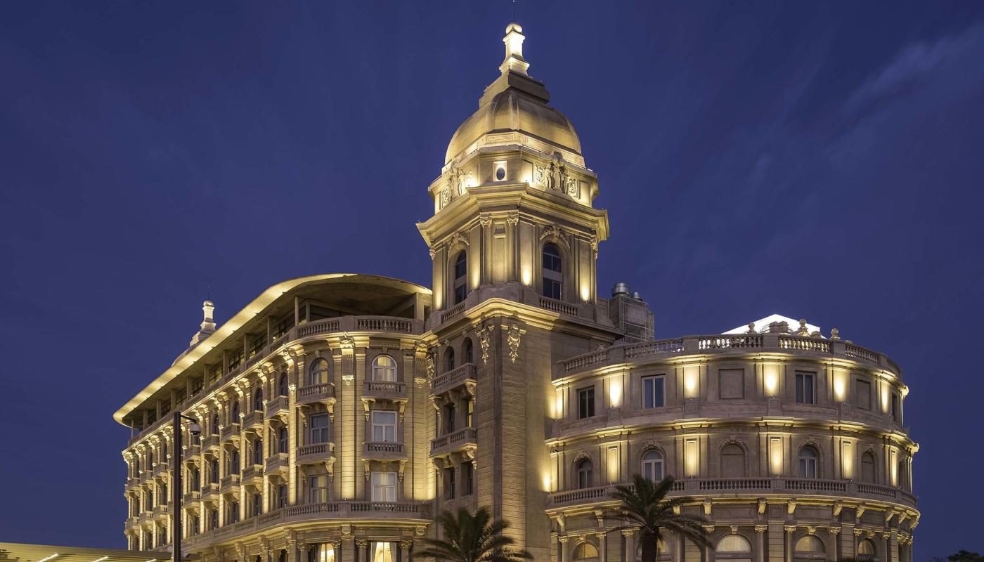 Fachada del hotel Sofitel Casino Carrasco en la tardecita noche. Los detalles arquitectónicos están destacados con luces verticales hacia arriba.