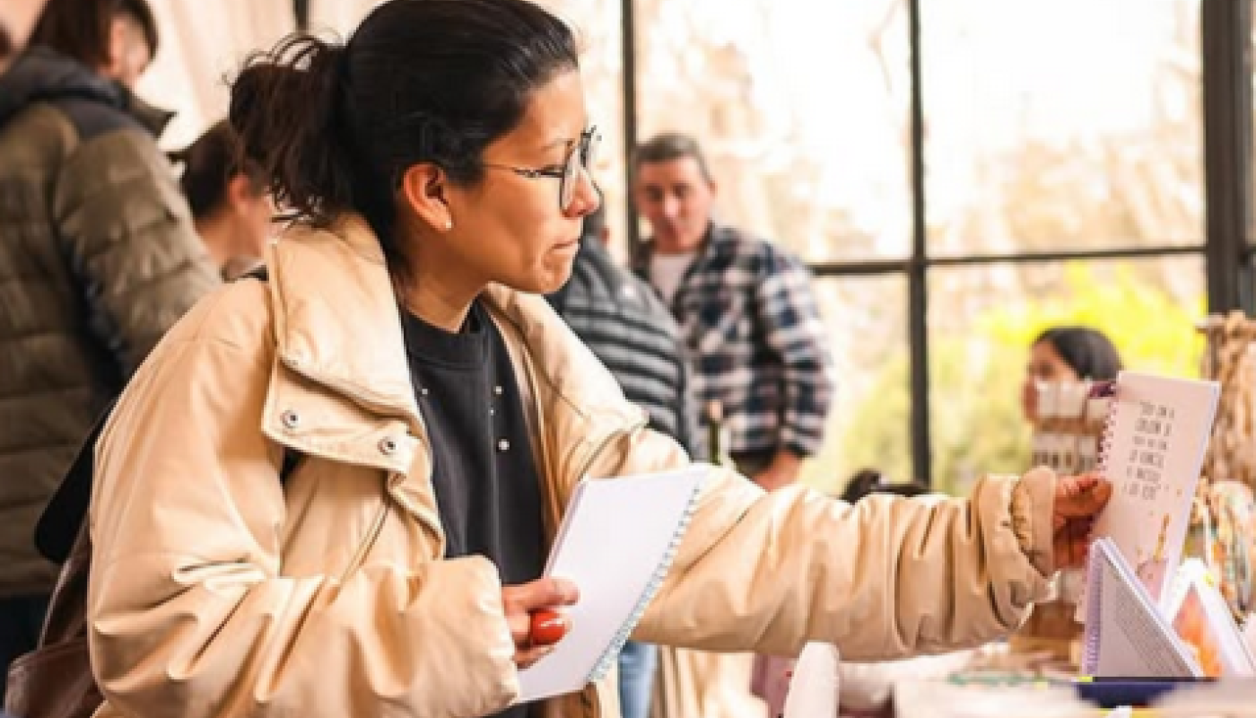Mujer observando un artículo en una mesa en un evento.