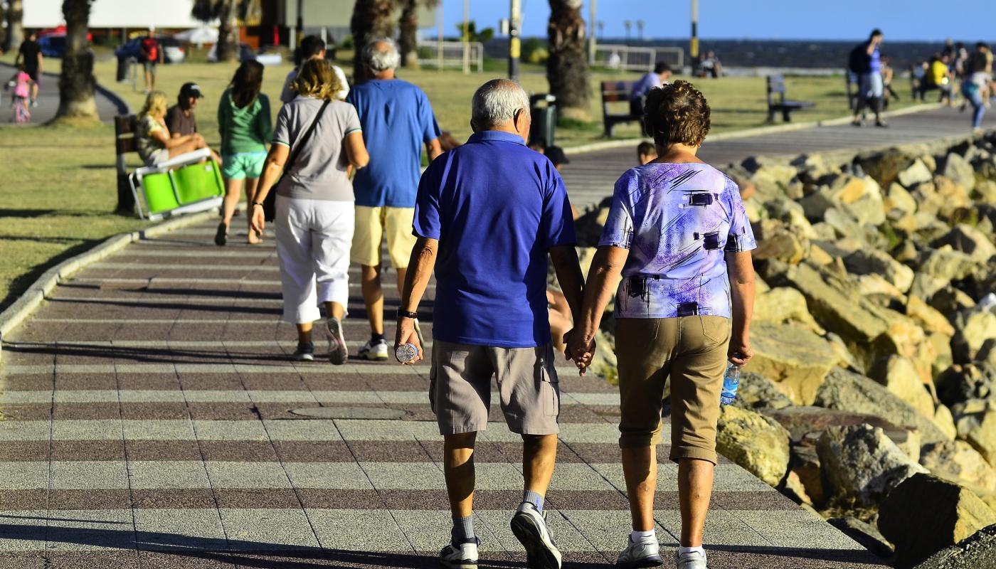 Pareja agarrada de la mano caminando por la ambla de Montevideo de día