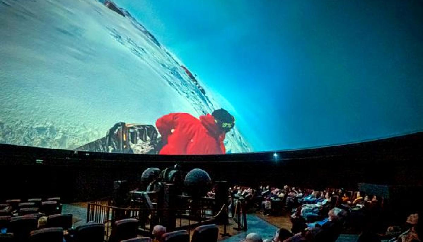 sala del planetario con èrsonas sentadas observando una función con el cielo celeste