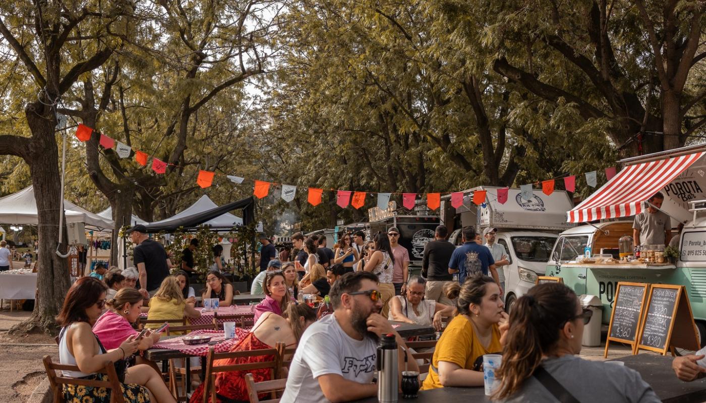 gente sentada en el parque almorzando en foodtruck 