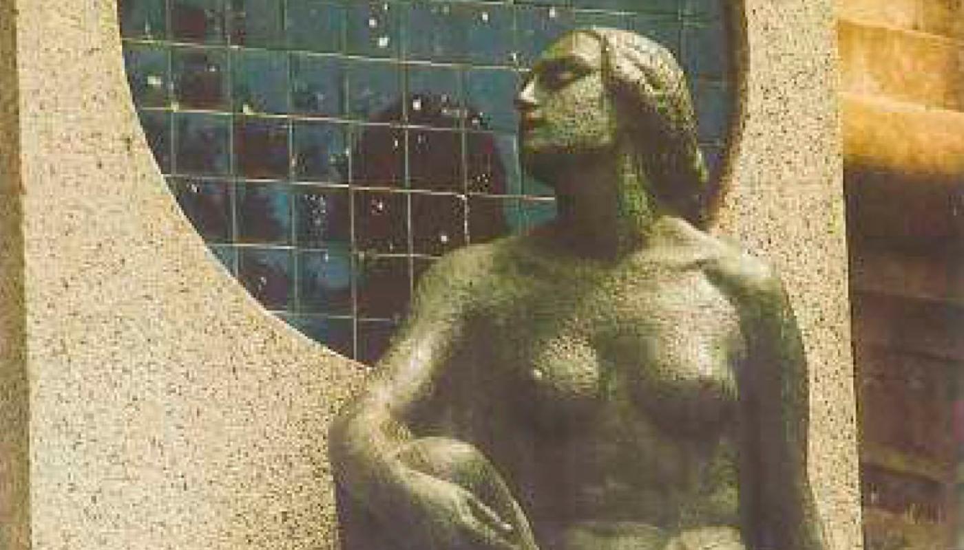 Se observa un pedestal de granito con un circulo de color azul y una escultura de mujer recostada en dicho circulo 