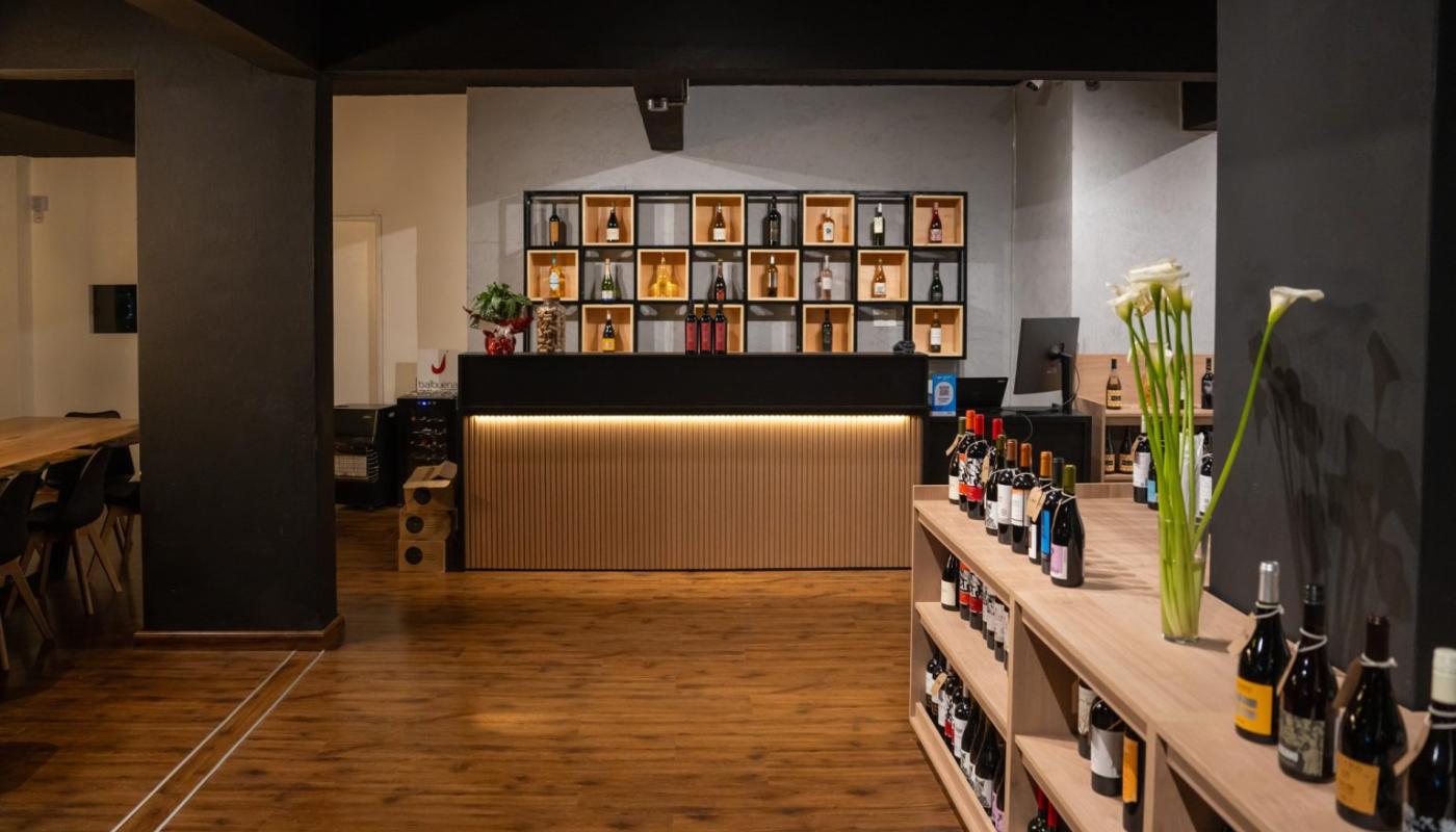 Ingreso al local con una barra para recepción y estantería de fondo con vinos 
