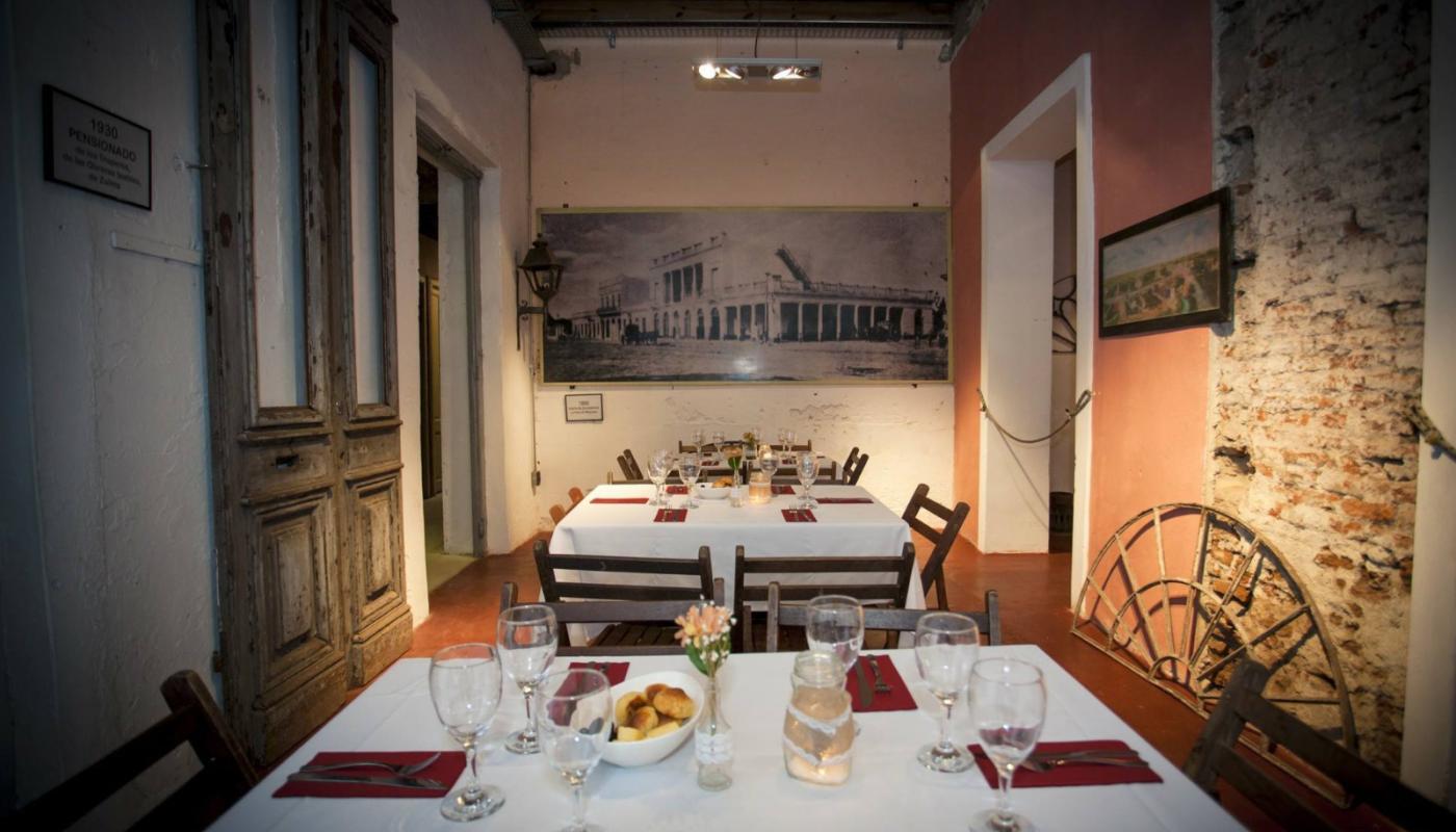 Imagen del comedor con las mesas con manteles elegantes y dispuestas para servir la comida 