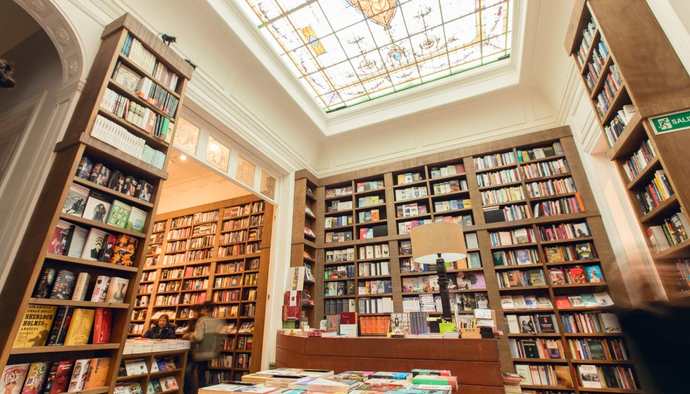 foto de la libreria escaramuza muestra de altas bibliotecas llenas de libros con vitral de fondo en su techo