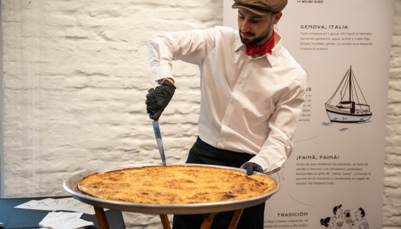 Presentación del día oficial del Fainá y una persona cortando fainá y degustando