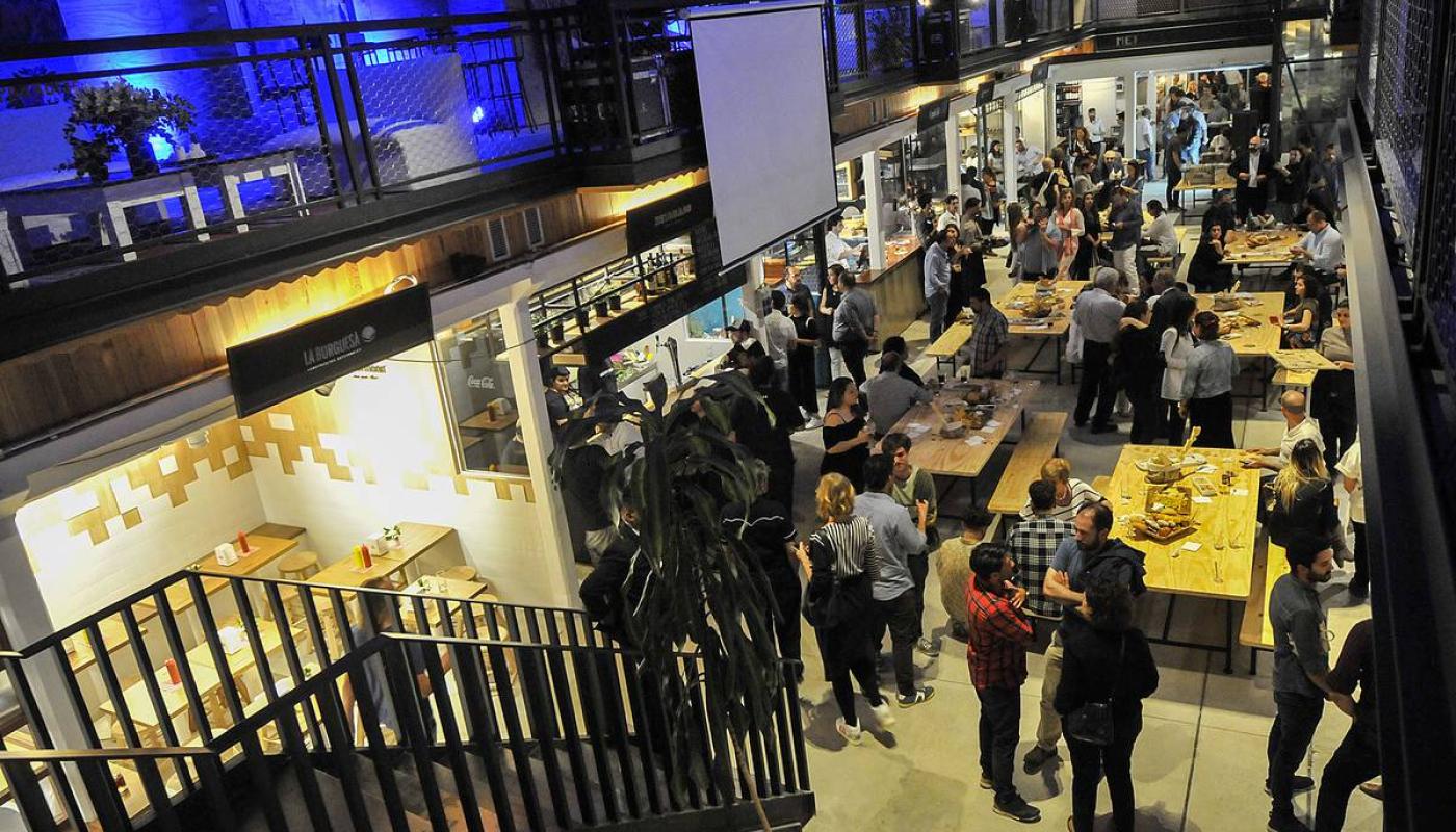 Foto del patio del Mercado con gente conversando, bailando, tomando y comiendo 