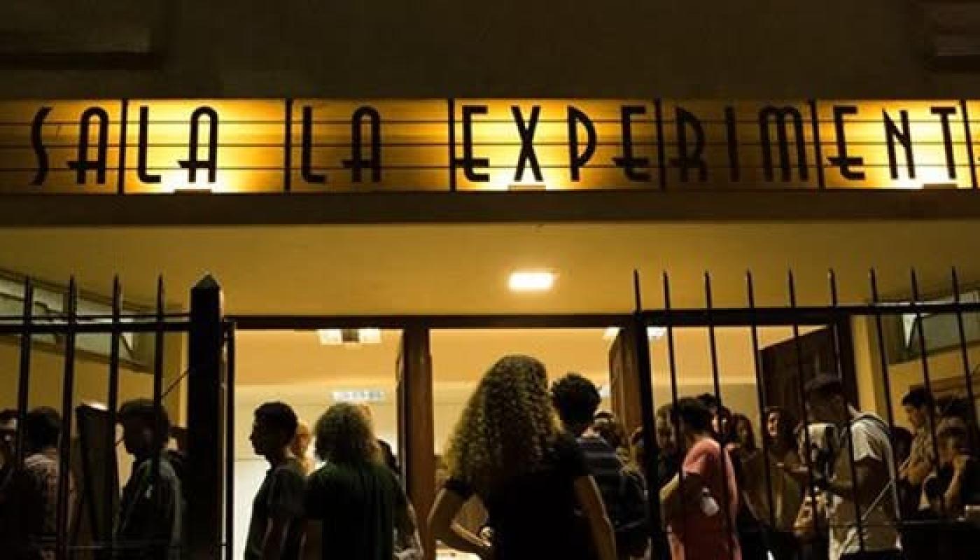 foto norcturna de la fachada del edificio iluminada con gente entrando a un espectáculo