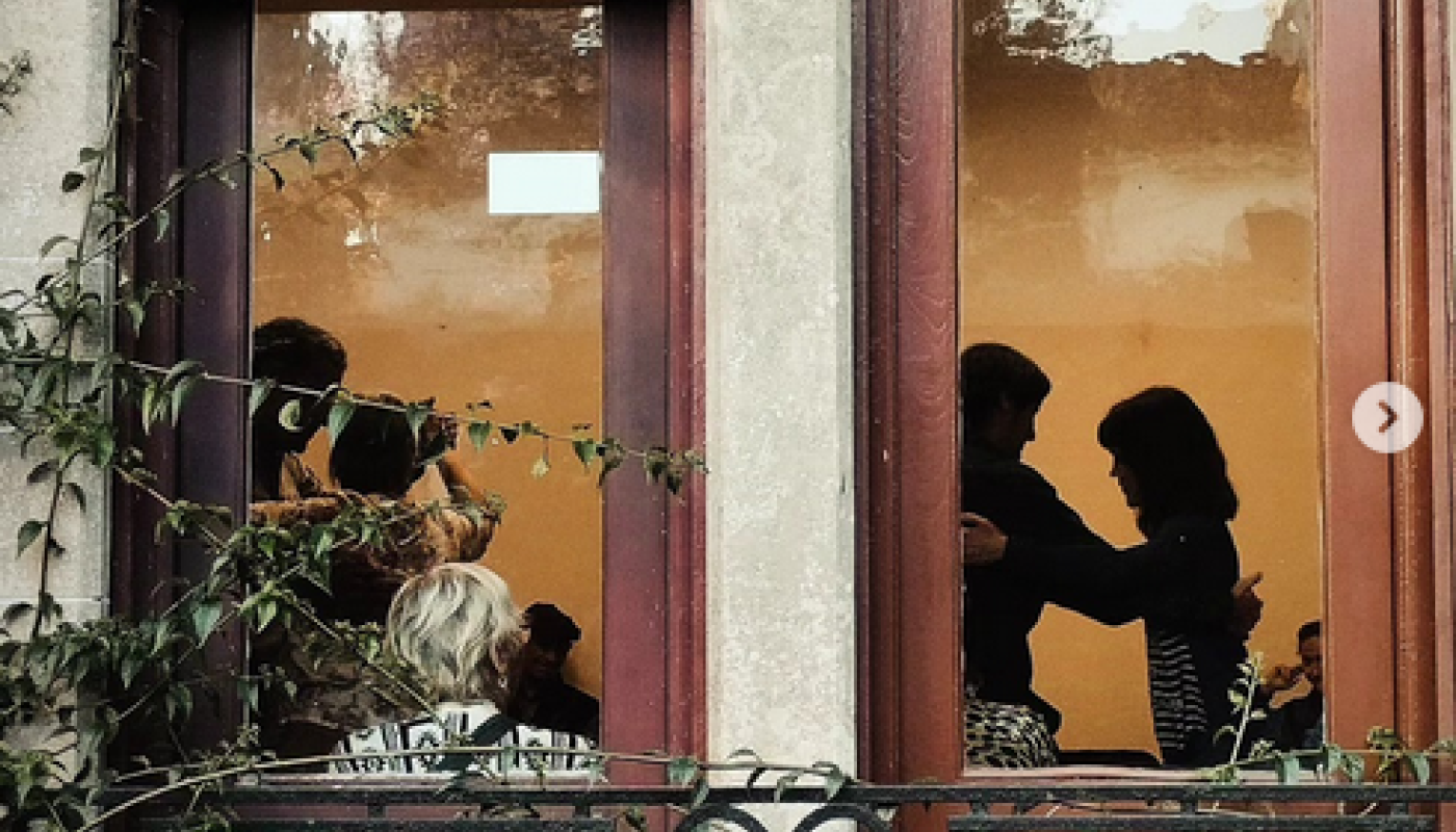 siluetas de personas bailando tango através de dos centans de maderadeeespacio cultural