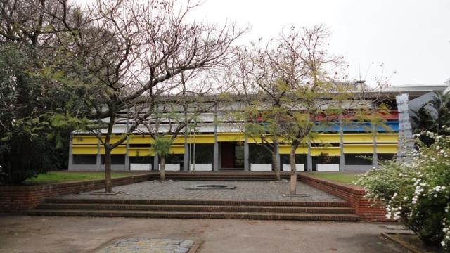 Foto exterior invernal del Museo. Fachada moderna en colores varios. Patio amplio con escalinatas.