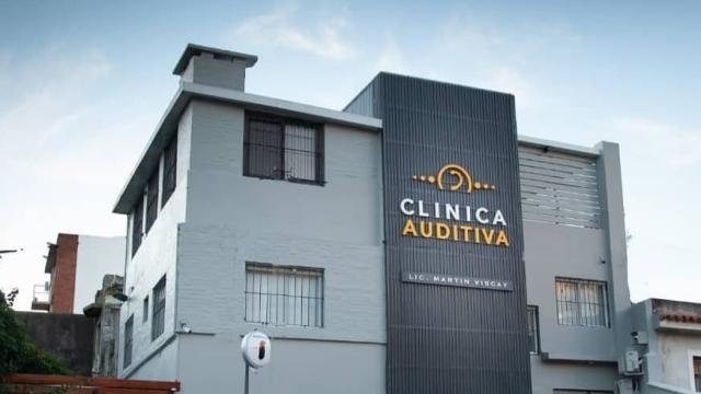 Sede de la empresa. Casa moderna en color gris de dos pisos con reja al frente. Cartel con nombre de la empresa en blanco y amarillo a lo largo de la fachada. 