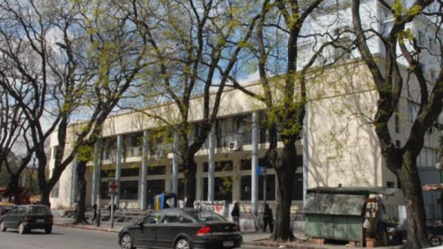 Fachada principal a la calle. Cuadra muy arbolada. Edificio moderno en color crema. Estructura vidriada con columnas. Ingreso con escalinata. 