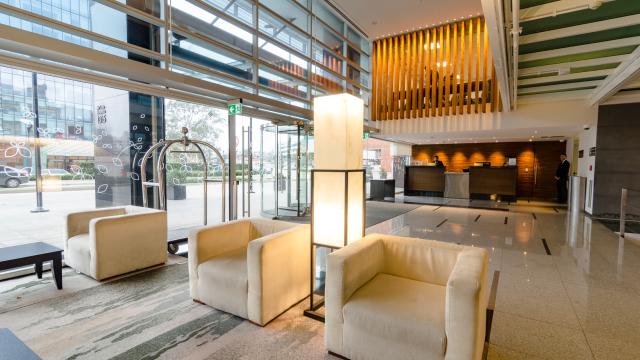 Lobby del hotel con la recepción al fondo y living en el centro con pared vidriada al exterior