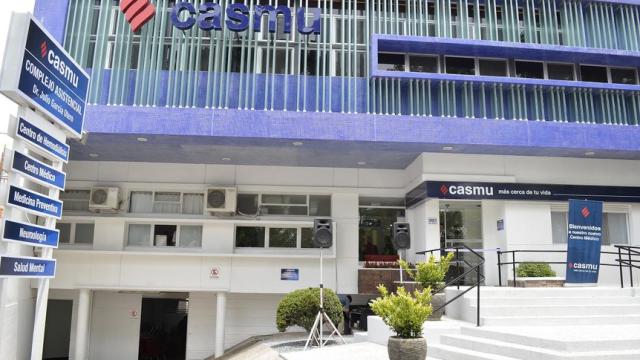 Edificio moderno con escalina principal blanca y rampa accesible. Frente blanco y azul como los colores de la empresa. Logo en diferentes partes de la fachada. 