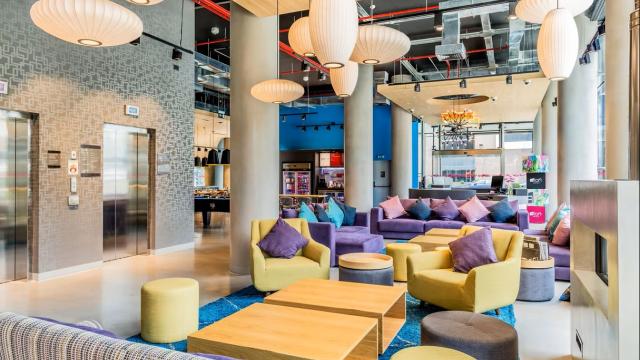 Lobby del hotel. Hay sillones de diversos tamaños y colores. Al fondo hay una mesa de pool, una heladera con bebidas y mesas con sillas.