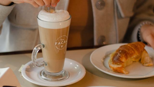 merienda bar facal: persona tomando un capuchino con medialunas y sandwiches