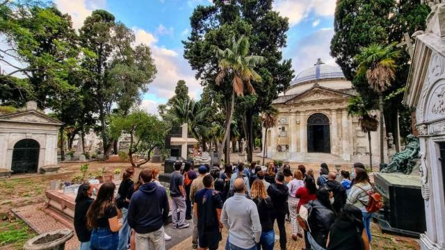 grupo de personas en un tour guiado apreciando esculturas y panteón nacional. Al fondo muchos árboles