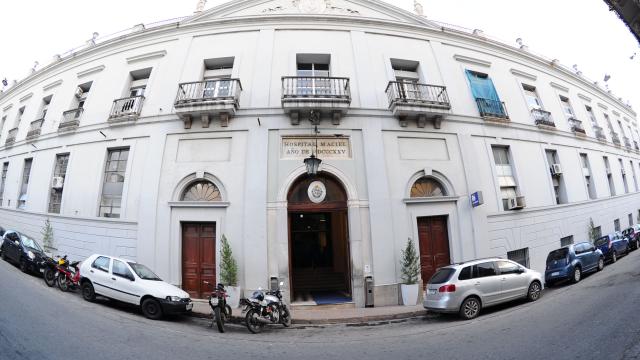 Foto tomada con angulo especial que da la impresión de estar el edificio apaisado. Edificio antiguo en varios pisos de color blanco. 