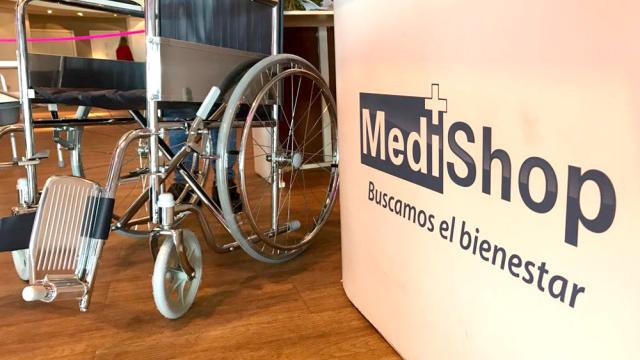 En una esquina de la foto hay una silla de ruedas. Y en la otra, un banner con el nombre de la empresa en letras grandes y azules. 