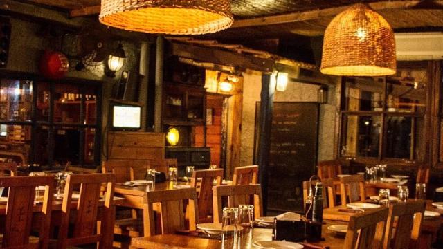 Foto del salón principal decorado con madera y lamparas de mimbre así como artículos de pesca dándole un toque rústico