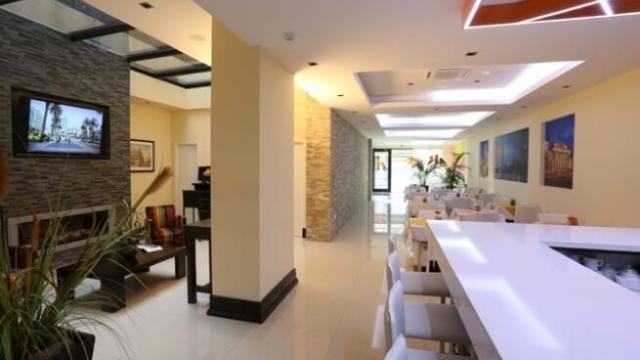 Interior del hotel. Hay algunas mesas con sillas y una barra con bancos altos.