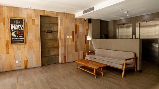 Parte del lobby del hotel. Hay un sofá de tres cuerpos y una mesa ratona de madera.
