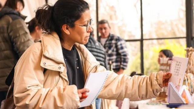 Mujer observando un artículo en una mesa en un evento.