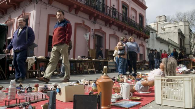 Personas recorren puestos de antigüedades y objetos usados en una feria callejera del barrio de Tristán Narvaja, en Montevideo.