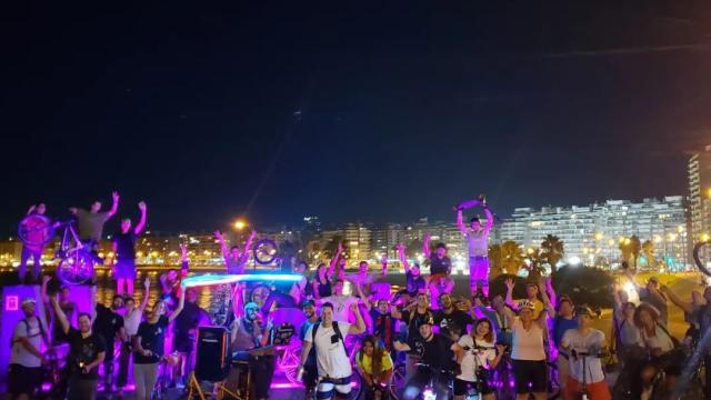 grupo de personas en rodados, patines, bicis con el fondo de la rambla de Montevideo atrás