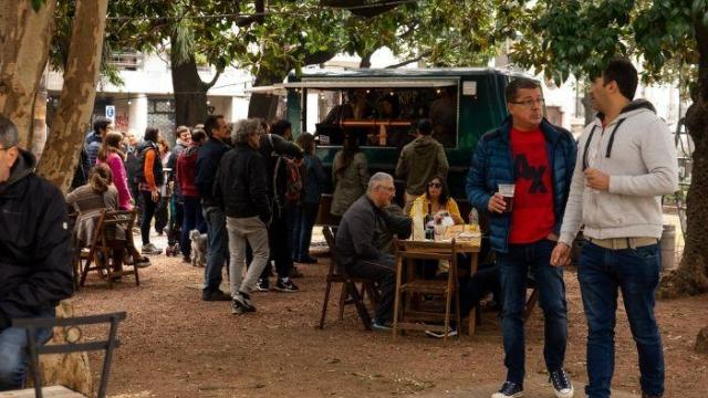 Plaza de ciudad vieja  con mucha gente disfrutándo de feria cultural con musicos , puestos gastronomicos y propuestas artisticas