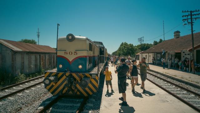 Foto de la locomotra principal del tren junto a gente esperando en la estación