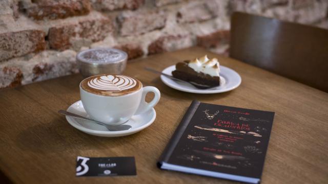 café y torta de chocolate con merengue con un libro negro sobre una mesa