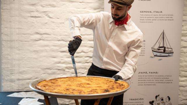 Presentación del día oficial del Fainá y una persona cortando fainá y degustando