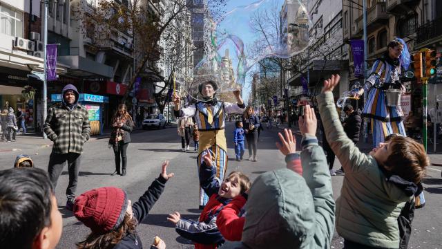 grupo de niños en 18 de julio hecha peatonal por el día d elas infancias juagando con burbujas gigantes y payasos