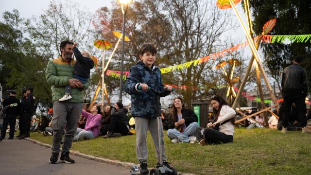 parque de la amistad,niño en monopatin sobre sendero con pasto verde de fondo y familas disfrutando del parque sentados