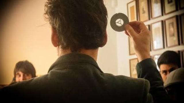 persona de espalda mostrando en un museo a publico de frente objeto fotográfico