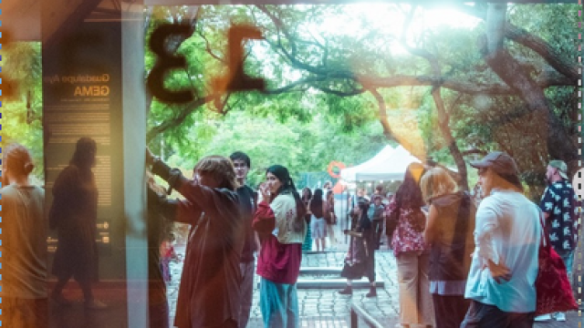 entrada del museo atraves del vidrio de muchas personas en el jardin del museo