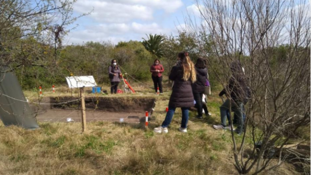 Foto del sitio arqueológico junto a los científicos que se encargan de recolectar datos